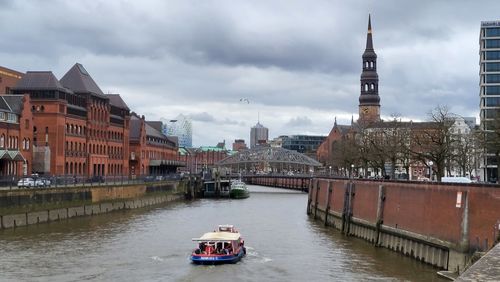 Buildings by river against sky