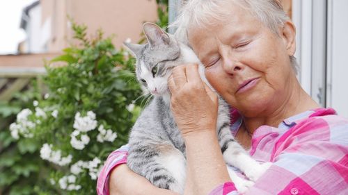 Senior woman with closed eyes embracing cat