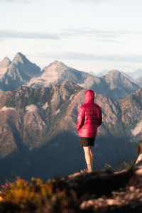 Rear view of man standing on mountain against sky