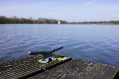 Close-up of rusty metal on pier by lake against sky