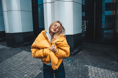 Young woman with eyes closed standing against building 