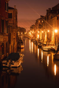 Canal amidst illuminated buildings against sky at night