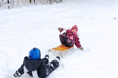 Cute kids playing on snow covered land during winter