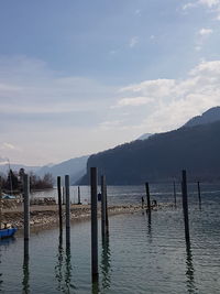 Wooden posts in lake against sky