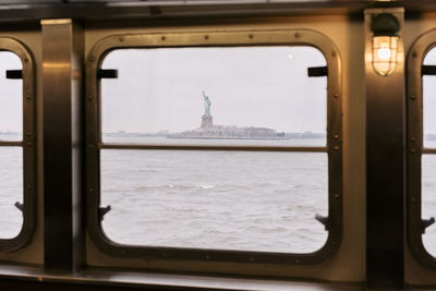 Statue of liberty seen through window of staten island ferry in hudson river