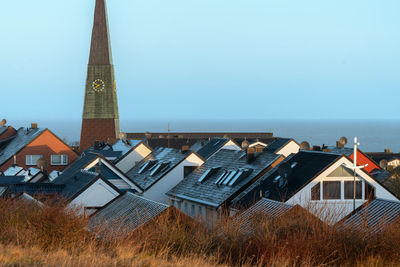 Houses by sea against clear sky