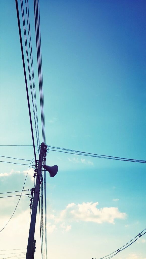 low angle view, connection, blue, power line, electricity, electricity pylon, cable, power supply, technology, clear sky, fuel and power generation, sky, silhouette, copy space, power cable, outdoors, no people, built structure, tall - high, pole