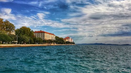 Buildings by sea against sky