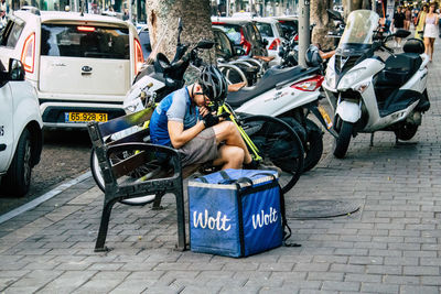 Man sitting on street in city