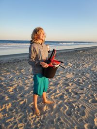 Woman standing on beach against sea against sky