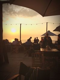 People sitting on chair at beach during sunset