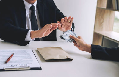 Cropped image of woman giving bribe to agent