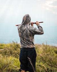 Rear view of man standing on field against sky