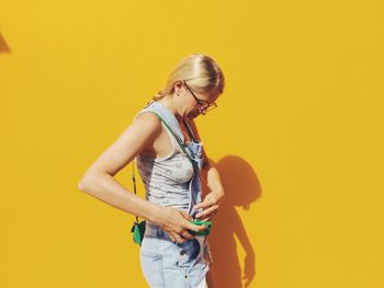 Side view of mid adult woman standing against yellow wall