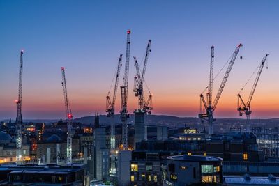 Illuminated factory against sky during sunset