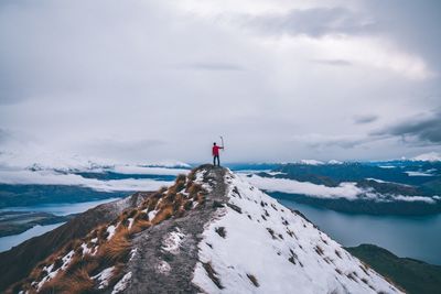 Man standing on snowcapped mountain against sky