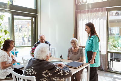 Female healthcare worker talking with elderly people at nursing home