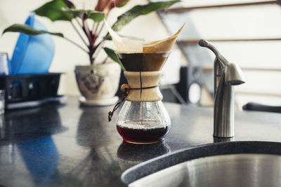 Coffee filter by faucet on kitchen counter