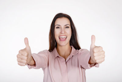 Portrait of happy mid adult woman showing thumbs up against white background