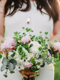 Midsection of woman holding bouquet of flowering plant