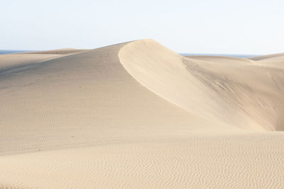 Sand dunes in desert against clear sky