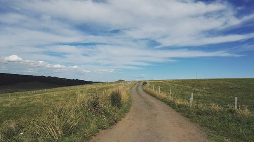 Road amidst field against sky