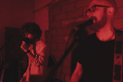 Group of musicians playing in red neon lights at music studio