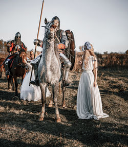 People riding horse on field against sky