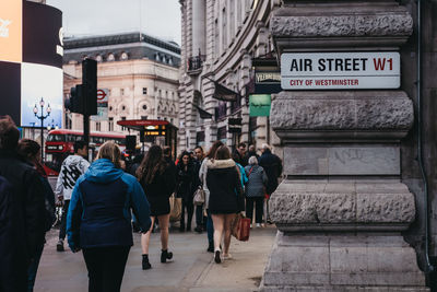 Rear view of people walking on street in city