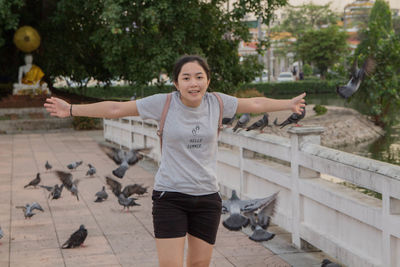 Portrait of young woman with arms outstretched standing on footbridge