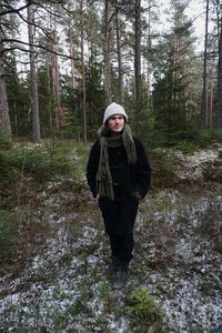 Full length of man wearing scarf walking against trees at forest