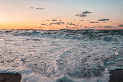 Scenic view of waves rushing towards shore during sunset