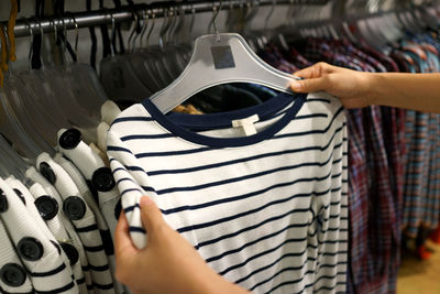 Cropped hands of woman buying t-shirt at store