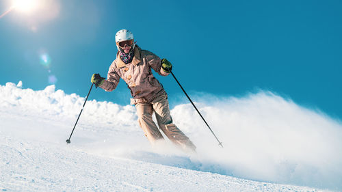 Low section of person skiing on snow against sky