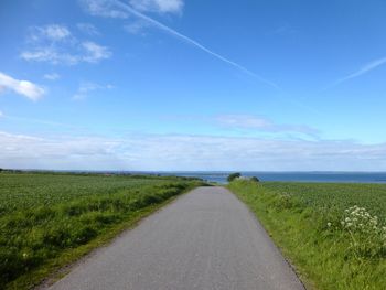 Country road against cloudy sky