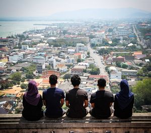 Rear view of people sitting in city against sky