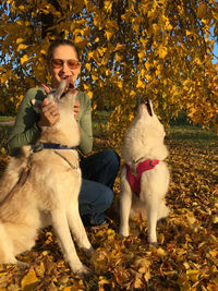 Young woman with dog on leaves during autumn