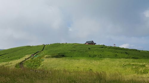 Panoramic view of green landscape against cloudy sky