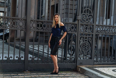 Portrait of woman standing against metal gate