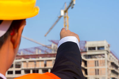 Businessman pointing at construction site against sky