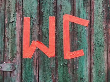 Close-up of red restroom sign on old wooden door