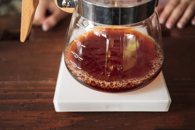 Close-up of hand pouring coffee in cup on table