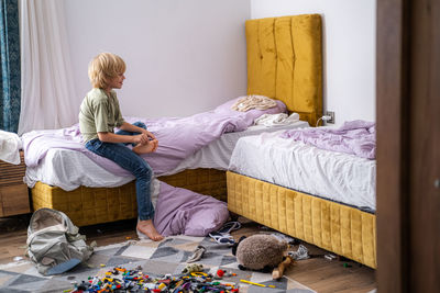 Young woman sitting on bed at home