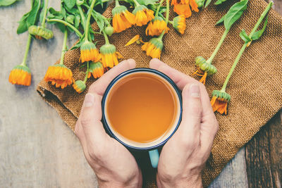 Cropped hand of woman holding drink on table