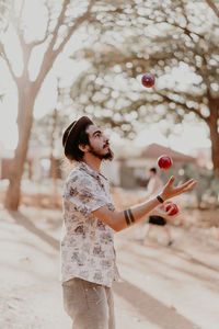 Young man juggling apples on sunny day