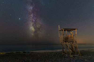 Lifeguard hut on beach against sky at night