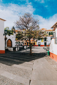 Road by houses and buildings against sky