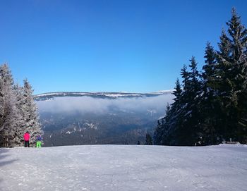 Scenic view of snow covered mountains against clear blue sky