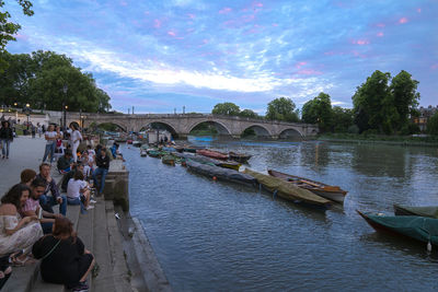 People on bridge over river against sky