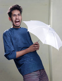 Portrait of young man standing against wall